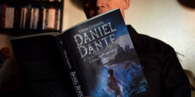 Silvio Coppola mentre sfoglia il suo libro Daniel Dante e la compagnia del Lumen magico